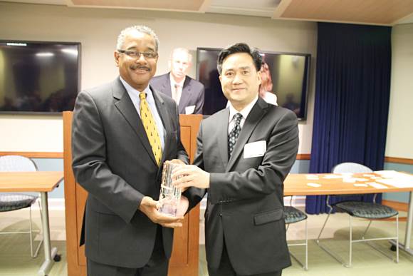 Mr. Frank Cao is presenting a gift to Mr. Antonio Doss